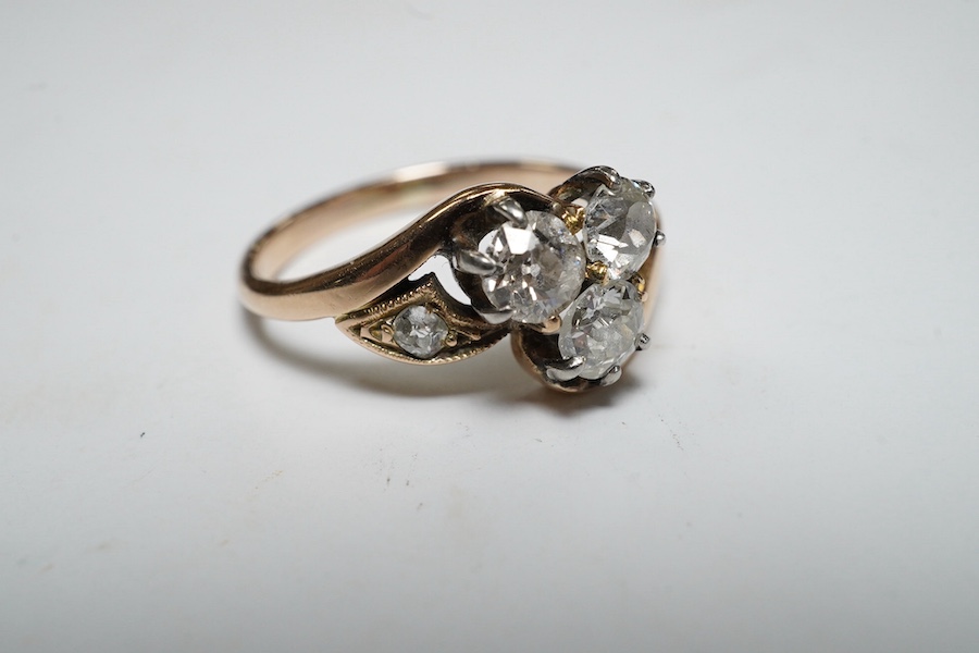 A yellow metal and three stone diamond set crossover ring, with single stone diamond set shoulder, size K, gross weight 2.4 grams. Condition - poor to fair